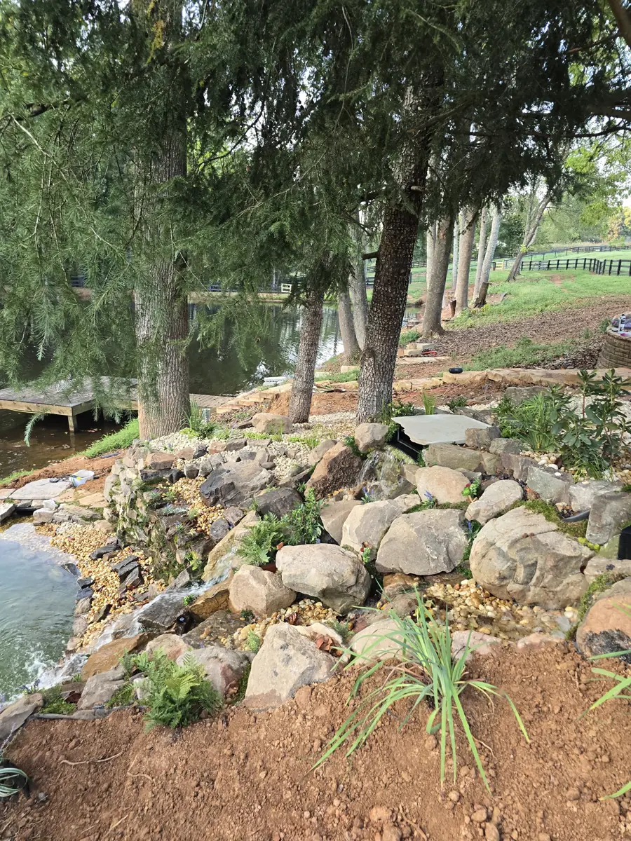 Boulder stream and waterfall built under pines on a lakeside lot